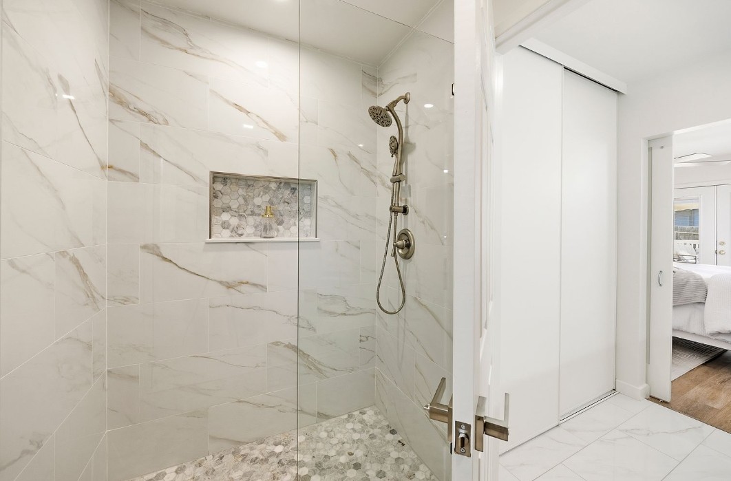 Walk-in shower with marble-look large format tile and hex mosaic floor